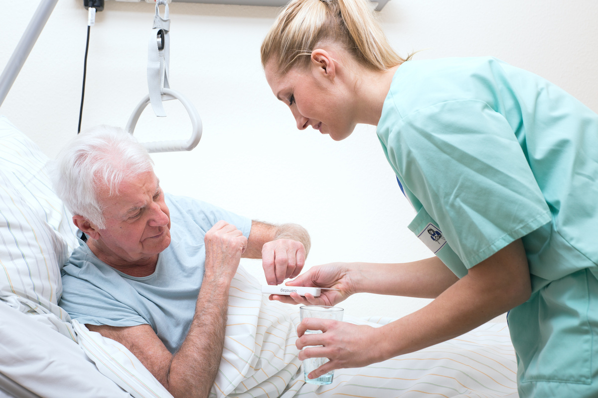 Senior mit Pflegerin im Altenheim Medikamenteneinnahme Langzeitpflege